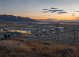 Cinematic view of a large data center campus and power infrastructure in an arid Utah landscape at dusk.